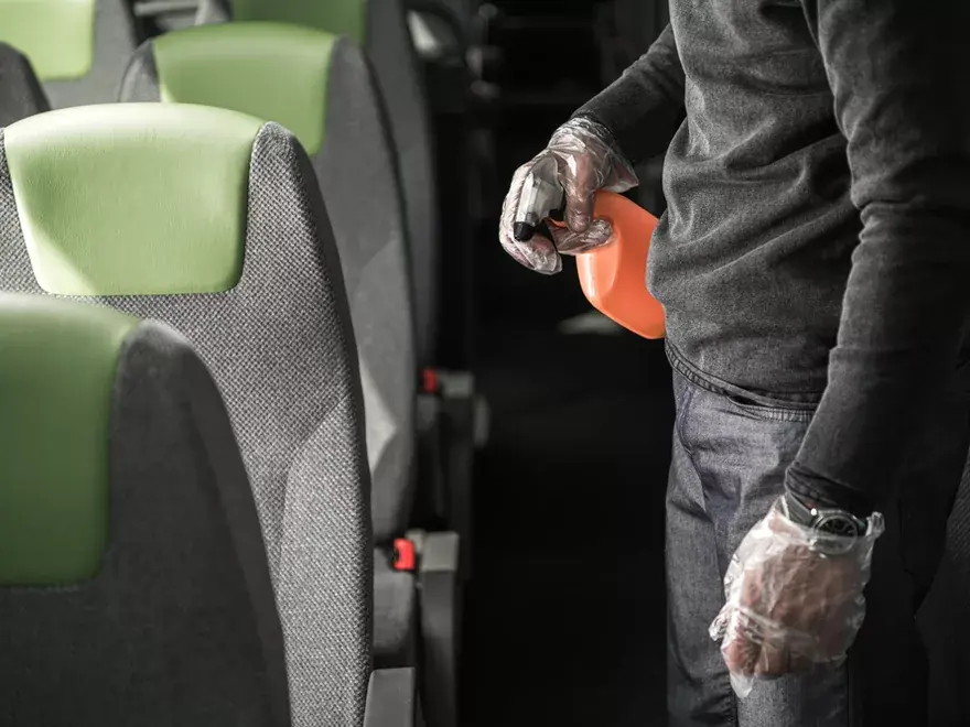 Professional cleaner sanitising seats inside passenger transport
