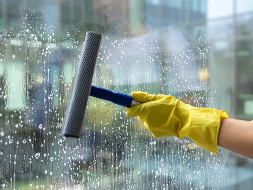 Professional window cleaner using a squeegee on commercial glazing